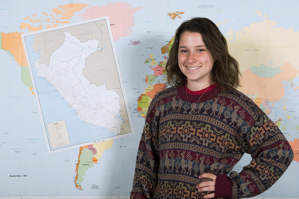 Mary Doro poses, smiling in front of a map of Peru