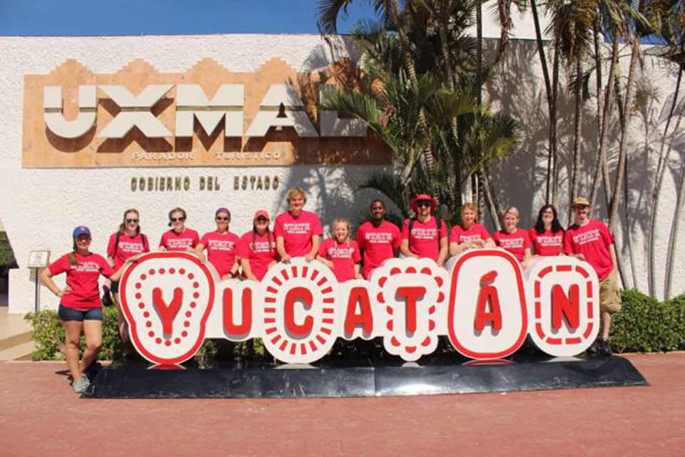 A group of students behind a sign that says Yucatan